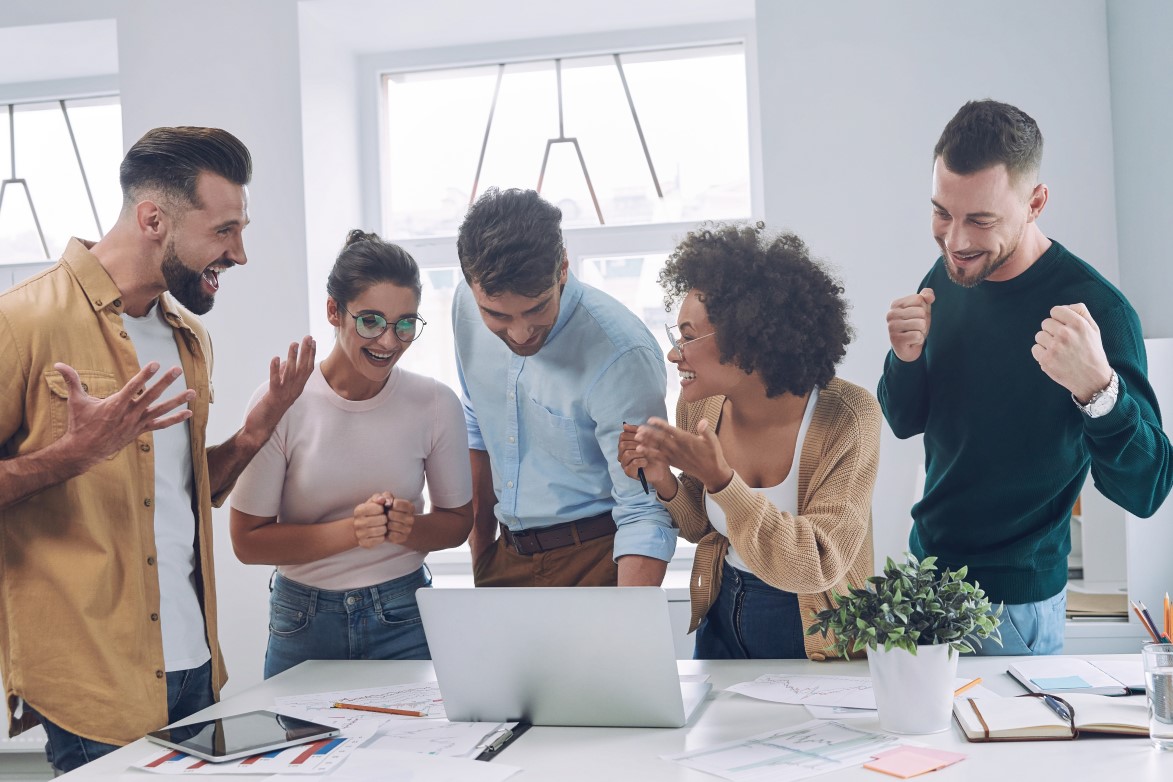 Group of happy business people in smart casual wear holding hands together and smiling