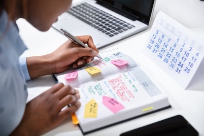 Businesswoman's Hand Checking Schedule In Diary