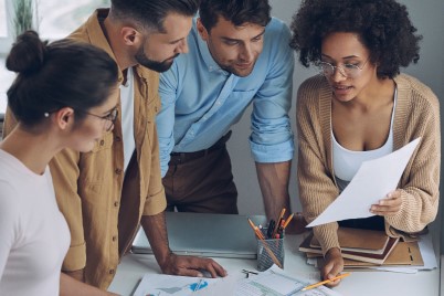 Confident young business team having quick meeting while standing in office together