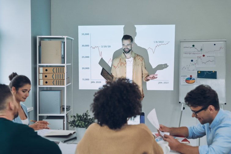 Group of young modern people in smart casual wear analyzing data on projection screen in the office